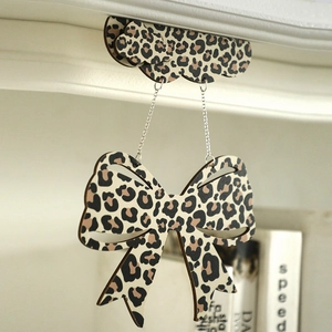 Close-up of leopard print bow pendant on minimalist light wooden shelf decoration
