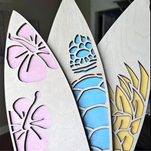 Detail of laser-cut wooden surfboard wall art with floral, turtle, and leaf patterns