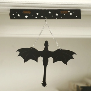 Detail of black flying dragon wall hanging on star-patterned bar with silver chain