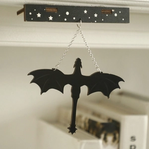 Close-up of a black wooden dragon wall hanging silhouette with silver chains
