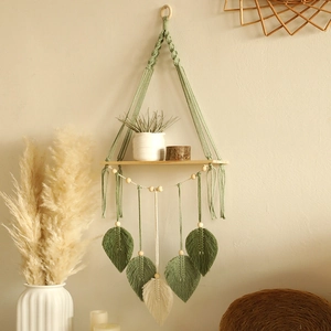 Handmade boho macrame wall shelf with sage green cotton leaves and a natural wood tray