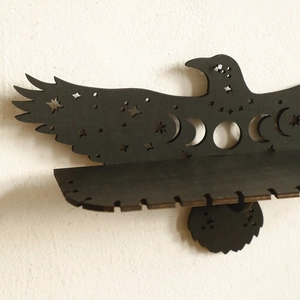 Eagle shaped black wooden wall shelf with star and moon phase cutout designs