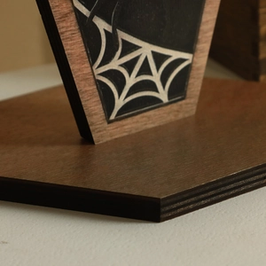 Detail view of gothic wooden Halloween ornament with spider web print and layered wood texture