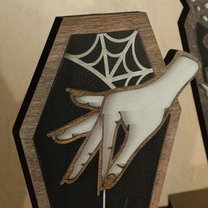Close-up of Gothic Halloween coffin-shaped wood plaque with spider web and pale hand design