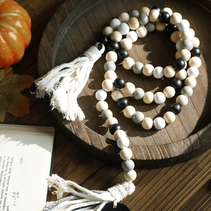 Dettaglio ghirlanda di perline in legno con nappe di cotone e zucche decorative