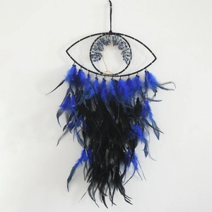 Detail view of eye-shaped dreamcatcher featuring a gold wire tree of life and blue feathers