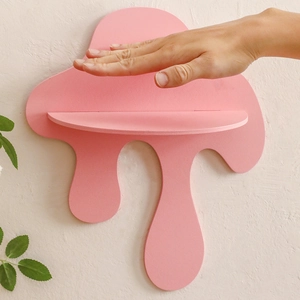 Close-up of pink liquid-drip shaped wooden wall shelf being held to show size