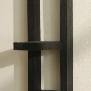 Detail of charred black wooden wall shelf showing fine grain texture and minimalist joint