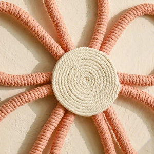 Close-up of hand-woven cotton rope flower wall decor with white center and pink petals