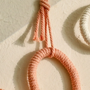 Detailed close-up of handmade peach pink cotton rope woven flower for wall decoration