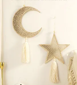 Close-up of laser-cut moon and star wood wall decor with long white cotton tassels