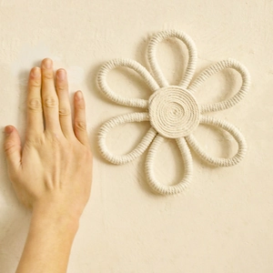Close-up of handmade cream cotton rope flower wall hanging with six-petal weave design