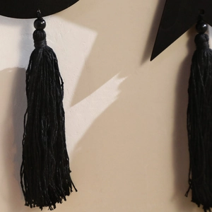 Detailed close-up of black moon and star wooden ornament with elegant cotton tassels