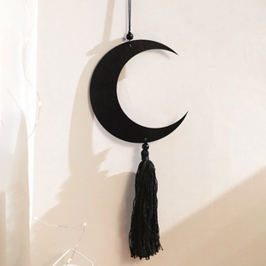 Detailed view of a black crescent moon wall hanging with fringe tassels and beads
