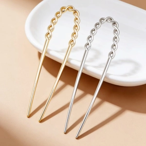 Detail view of twisted woven metal hair fork in gold and silver finish on porcelain