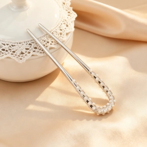 Épingle à cheveux argentée en U avec perles blanches sur fond de satin champagne