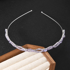 Detail van een zilveren metalen haarband met paarse strass-steentjes op zwarte achtergrond