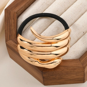 Irregular gold metal hair tie with black high-elastic rope on a beige jewelry tray