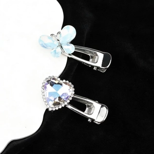 Close-up of silver hair clips with blue butterfly opal and rhinestone heart design