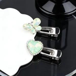 Detailed view of silver bow and heart hair clips with green stones and rhinestones