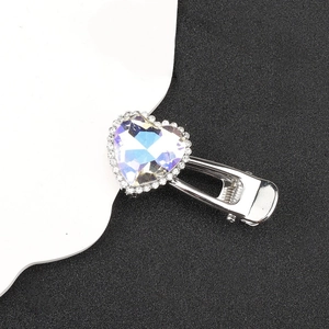 Close-up of heart-shaped iridescent gemstone hair clip with rhinestones on silver base