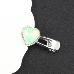 Detail view of heart-shaped silver clip with a light green gem and sparkling rhinestones