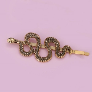 Close-up of vintage gold snake hairpin with textured scales and secure metal clip