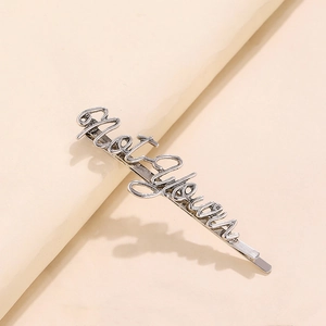 Detailed macro view of vintage silver Halloween letter hair clip with aged metal texture