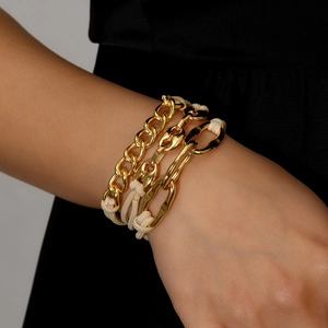 Schickes mehrlagiges Goldketten- und cremefarbenes Webseil-Armband Haargummi am Handgelenk