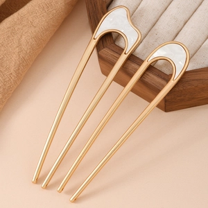 Close-up of a pair of gold U-shaped hairpins with elegant white mother-of-pearl inlay