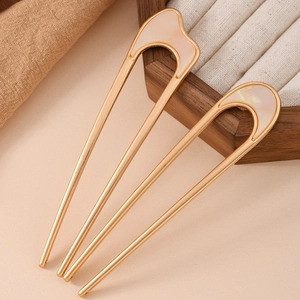 Detail of U-shaped gold alloy hairpins with cream pearlescent inlay on wood tray