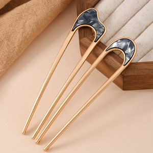 Detailed macro view of minimalist gold U-shaped hairpins with marble texture inlays