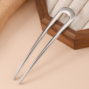 Macro shot of minimalist silver U-shaped hair pin on a hexagonal wooden jewelry box