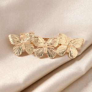 Elegant gold-plated spring hair clip featuring three connected butterfly designs on satin