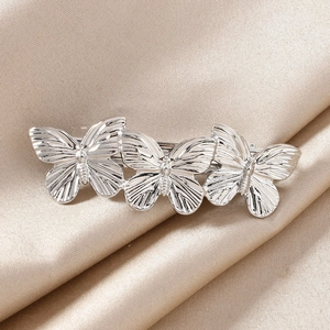 Three-butterfly silver spring hair clip with metal texture on champagne satin background