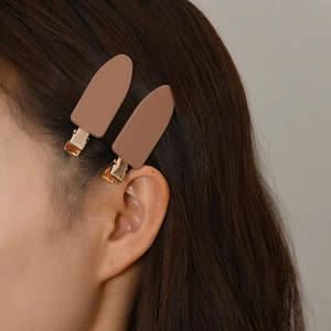 Gros plan de pinces à cheveux camel mat avec texture lisse et base en métal doré