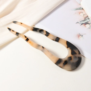 Minimalistische Haarnadel in U-Form aus Schildpatt-Resin auf elegantem Satin-Hintergrund
