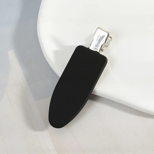 Détail macro d'une pince à cheveux mate noire sans trace avec clip en métal argenté