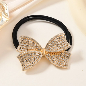 Detailed macro view of a gold rhinestone bow hair tie with elastic black bands