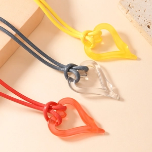 Three translucent resin heart necklaces in yellow orange and clear on woven cord