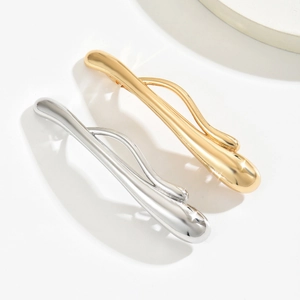Macro shot of minimalist liquid metal hair clips in polished gold and silver finishes