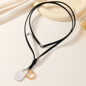 Detail showing gold and silver metal charms on a minimalist long black rope necklace