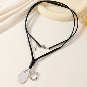 Close-up of black leather cord necklace with silver oval charm and lobster clasp detail