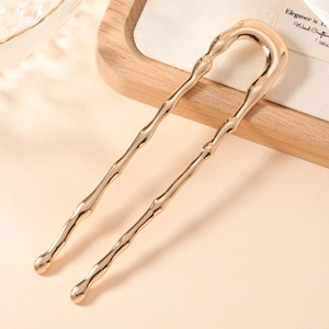 Macro view of rose gold U-shaped metal hair pin featuring a polished bamboo texture