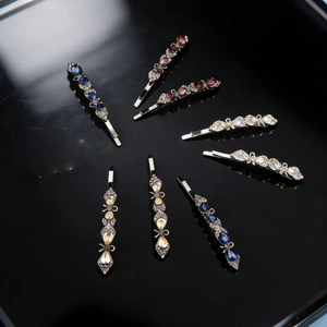 Close-up of 8-piece elegant alloy hair clips with colorful crystals on a black mirror
