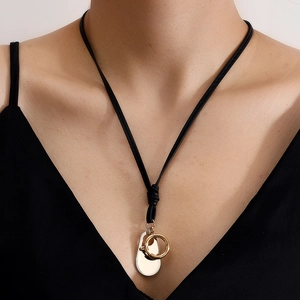 Minimalist long black cord necklace featuring gold ring and silver oval pendants on a model