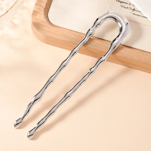 Silver U-shaped metal hair pin with bamboo design on a wooden tray background