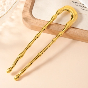 Close-up of golden U-shaped hair pin with bamboo texture and glossy metal finish