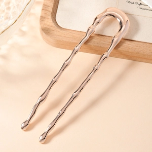 Macro detail of rose gold U-shaped metal hairpin with elegant bamboo wave texture