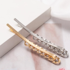 Minimalist gold and silver hair clips with chain detail on geometric display